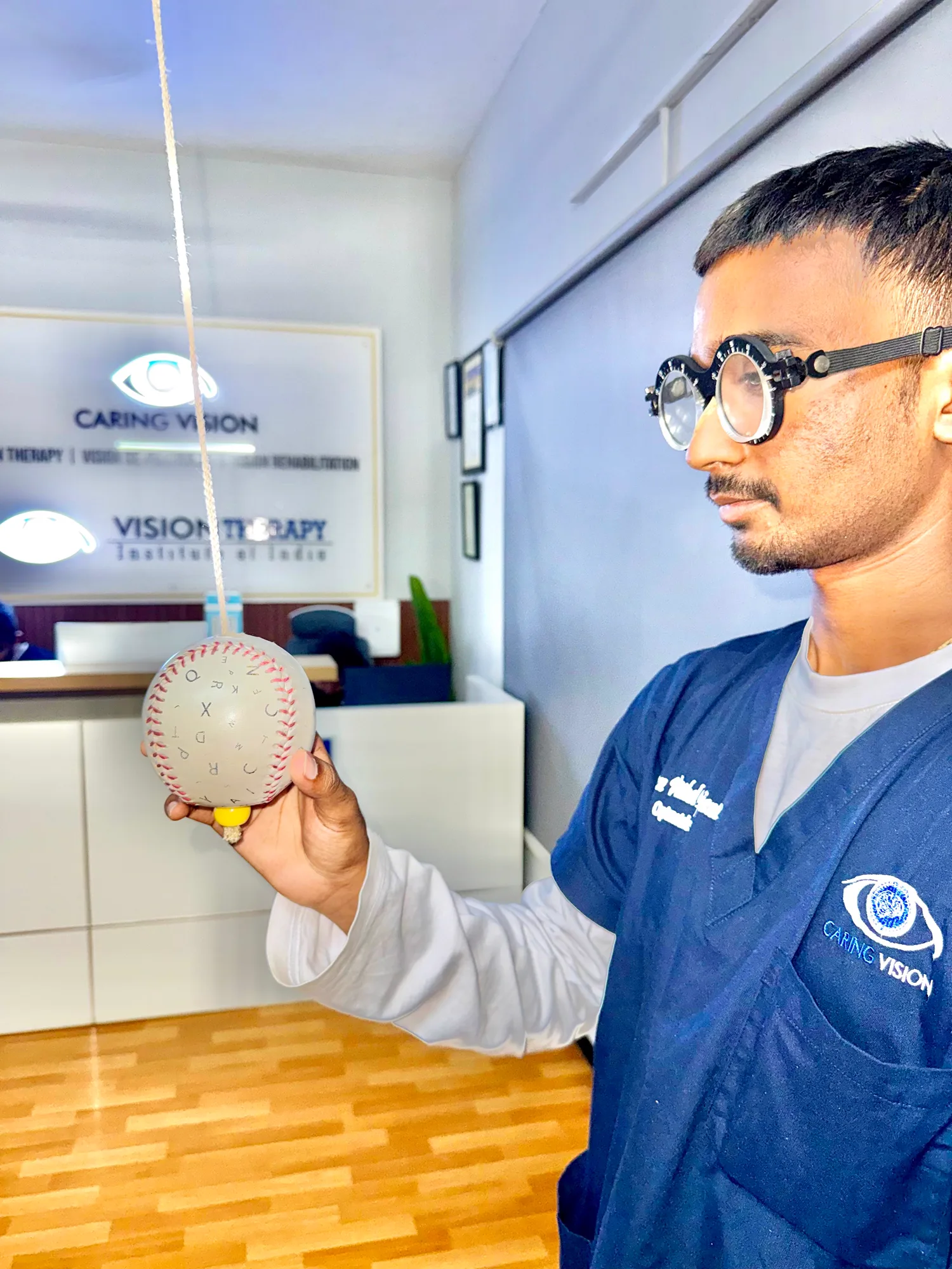Optometrist wearing trial frames performing Marsden ball vision therapy training at Caring Vision, Ashok Nagar