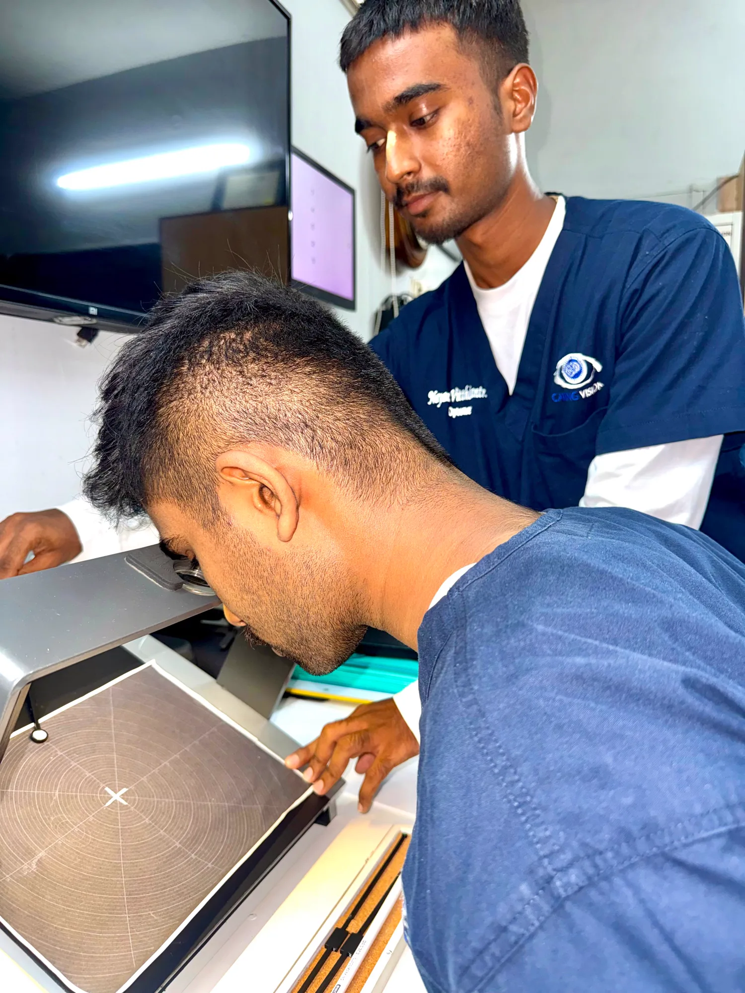 Senior optometrist mentoring a trainee during a visual field assessment at Caring Vision